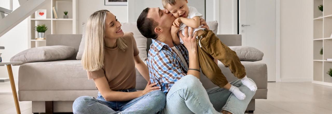 Happy young family with kid playing enjoying time together at home in living room