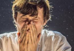 man sneezing indoors