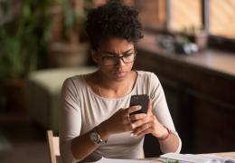 woman at home looking at phone confused