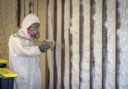 worker applying spray-foam insulation to a wall