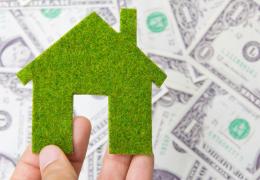 green home model over dollar bills, energy audit savings concept