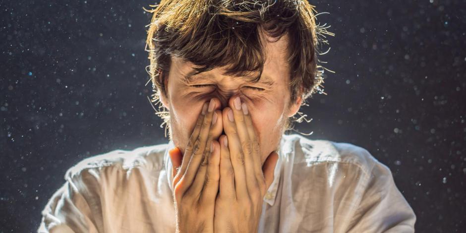 man sneezing indoors