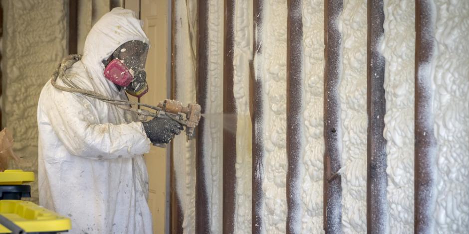 worker applying spray-foam insulation to a wall