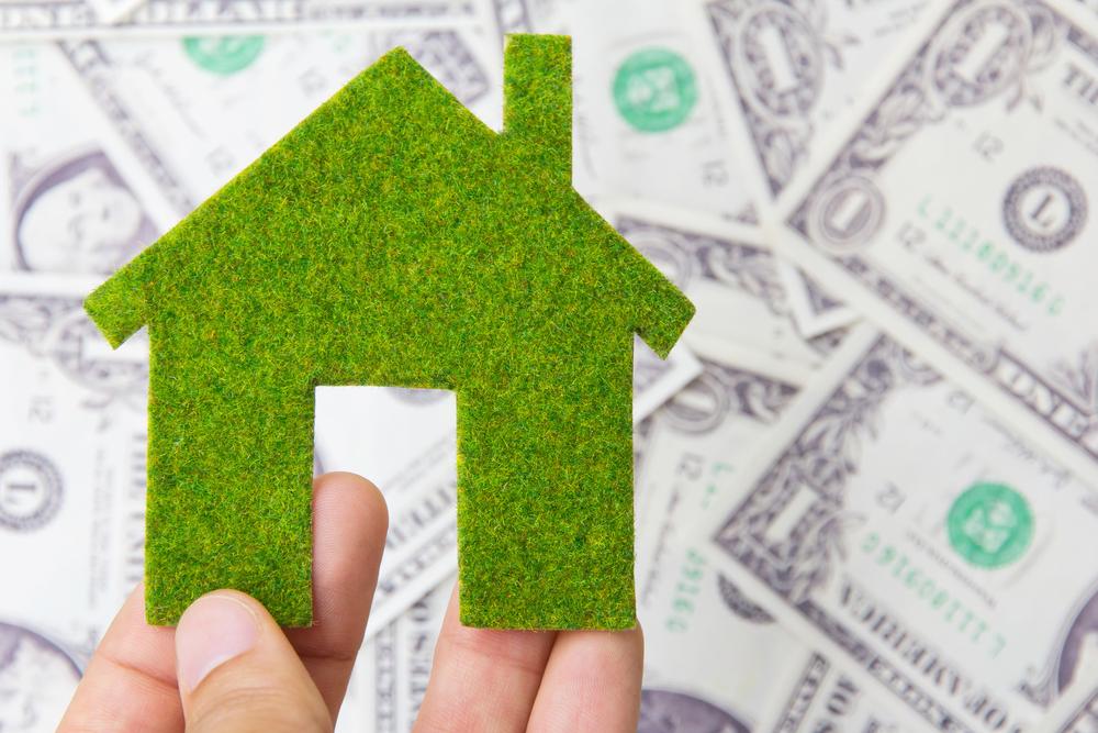 green home model over dollar bills, energy audit savings concept